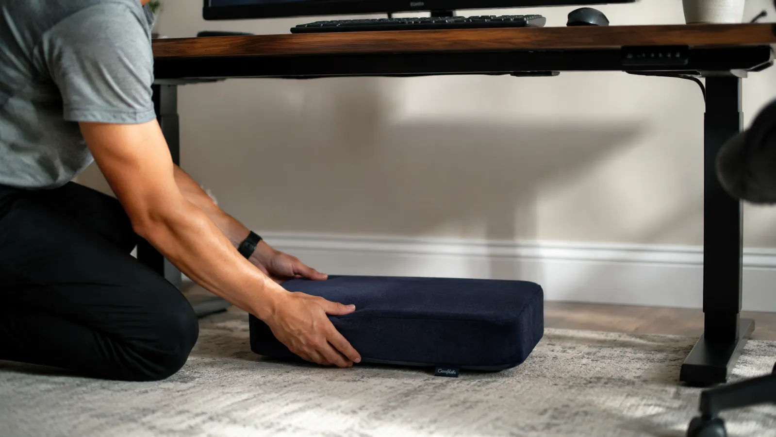Person sliding a memory foam footrest into position under a clean home office desk without any tools