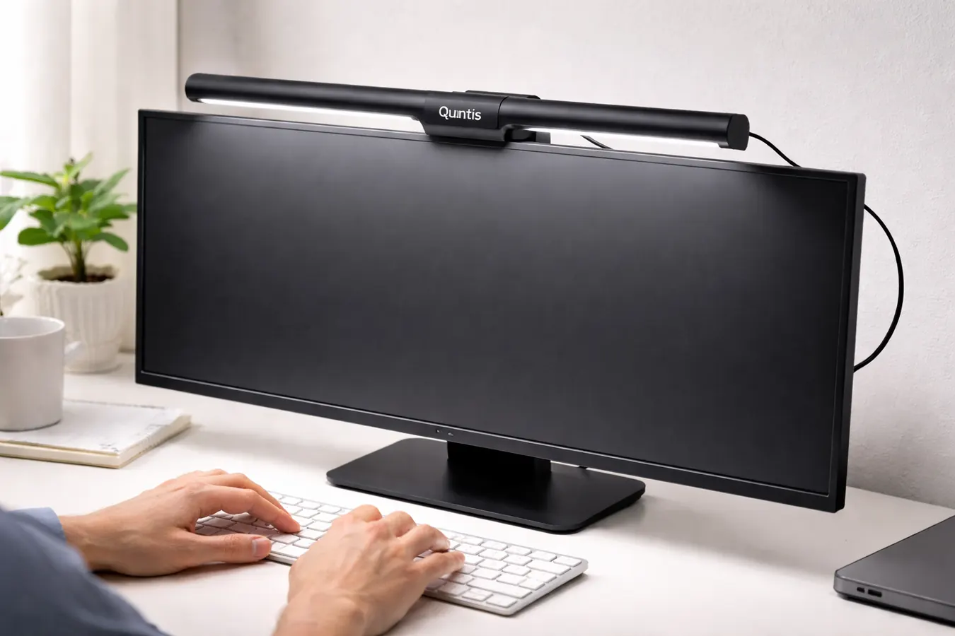 Quntis monitor light bar clipped onto the top of a widescreen monitor, USB cable routed down the back of the screen
