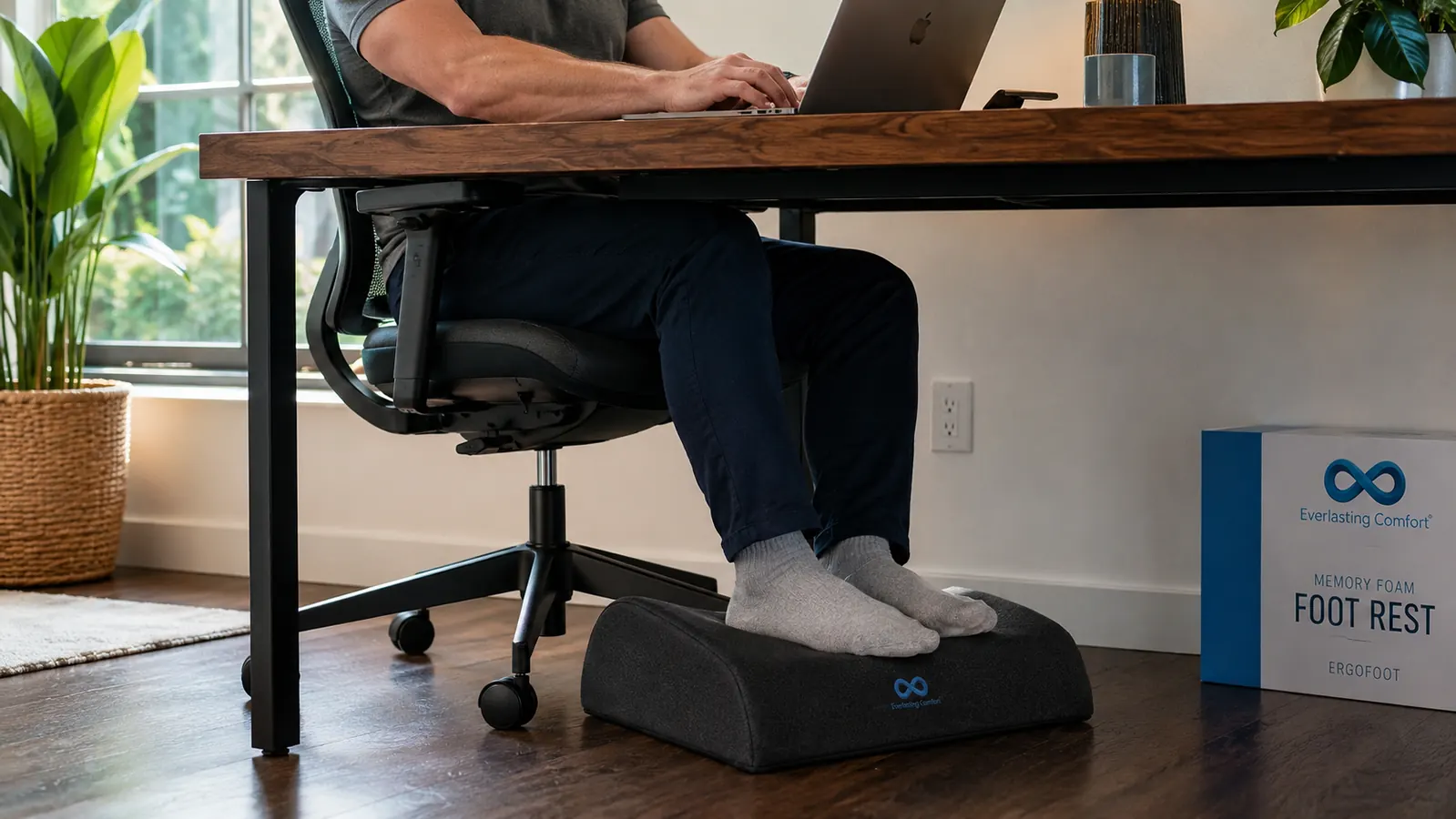 Close-up of the Everlasting Comfort memory foam footrest positioned under a desk, feet resting on its velvet surface