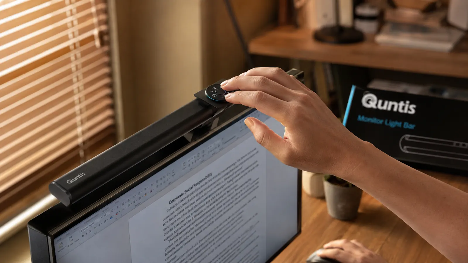 Close-up of hands adjusting the touch control on the Quntis monitor light bar, showing the warm and cool color temperature dial
