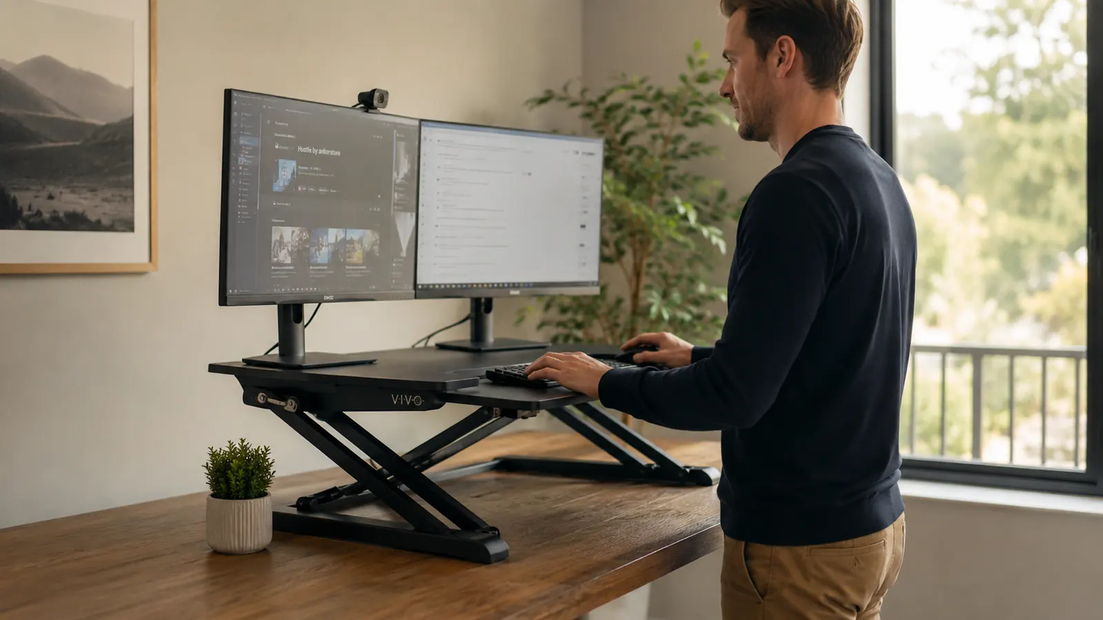 VIVO 32-inch desk converter raised to standing height on a wooden desk in a bright home office, dual monitors mounted on the platform